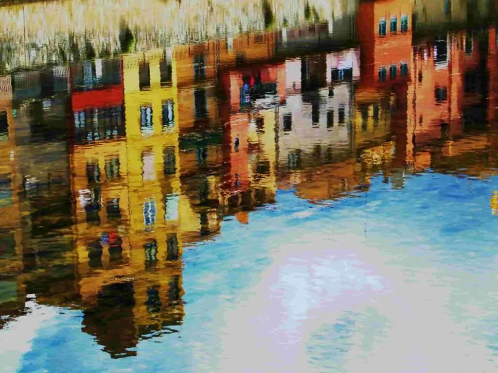 An oil painting which is representing the reflection of buildings on the water surface. 